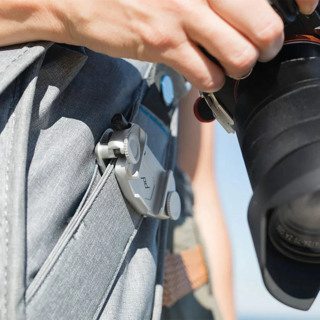 Srebrny uchwyt na aparat do plecaka, idealny dla fotografów w terenie