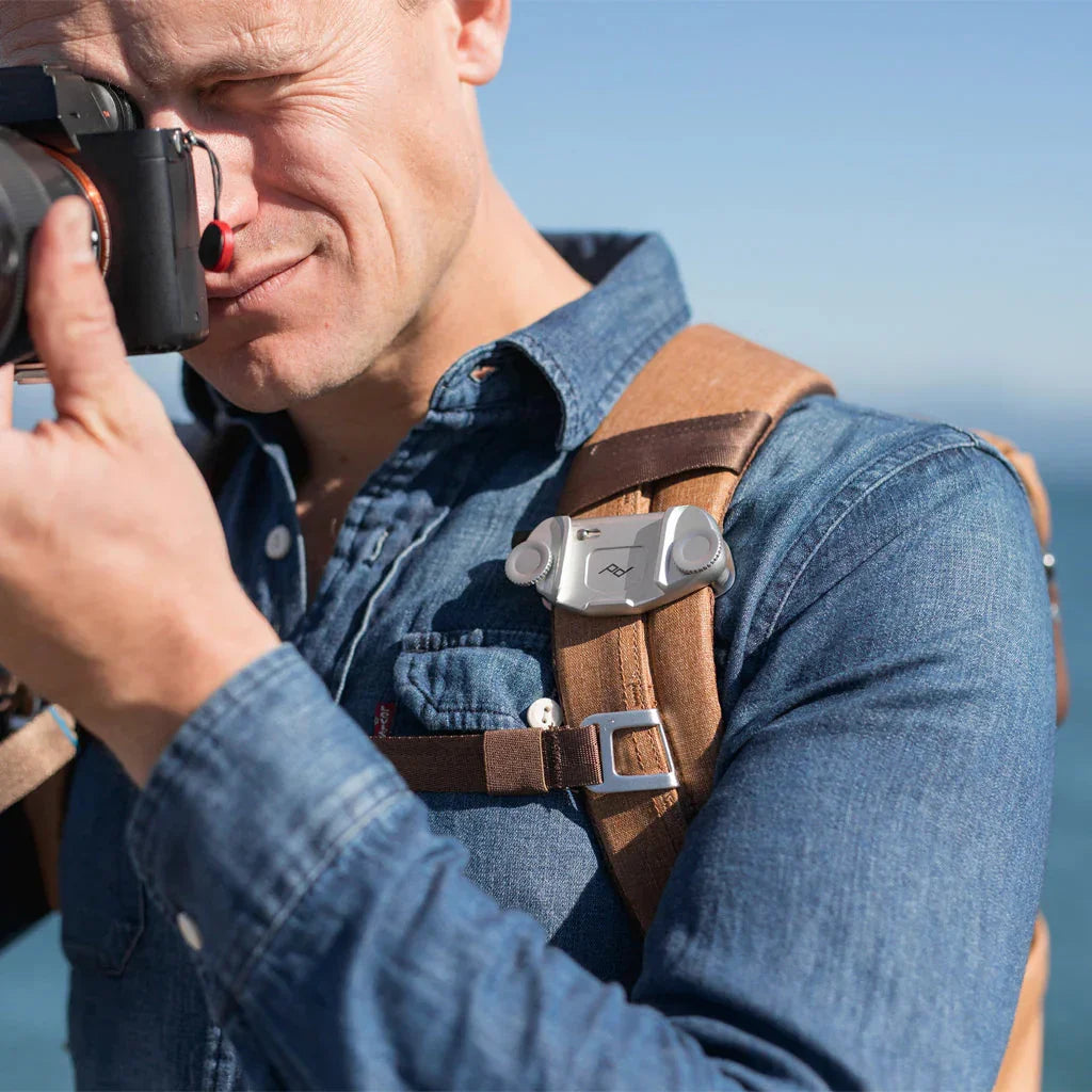 Mężczyzna z aparatem fotograficznym i akcesoriami do plecaka na zewnątrz
