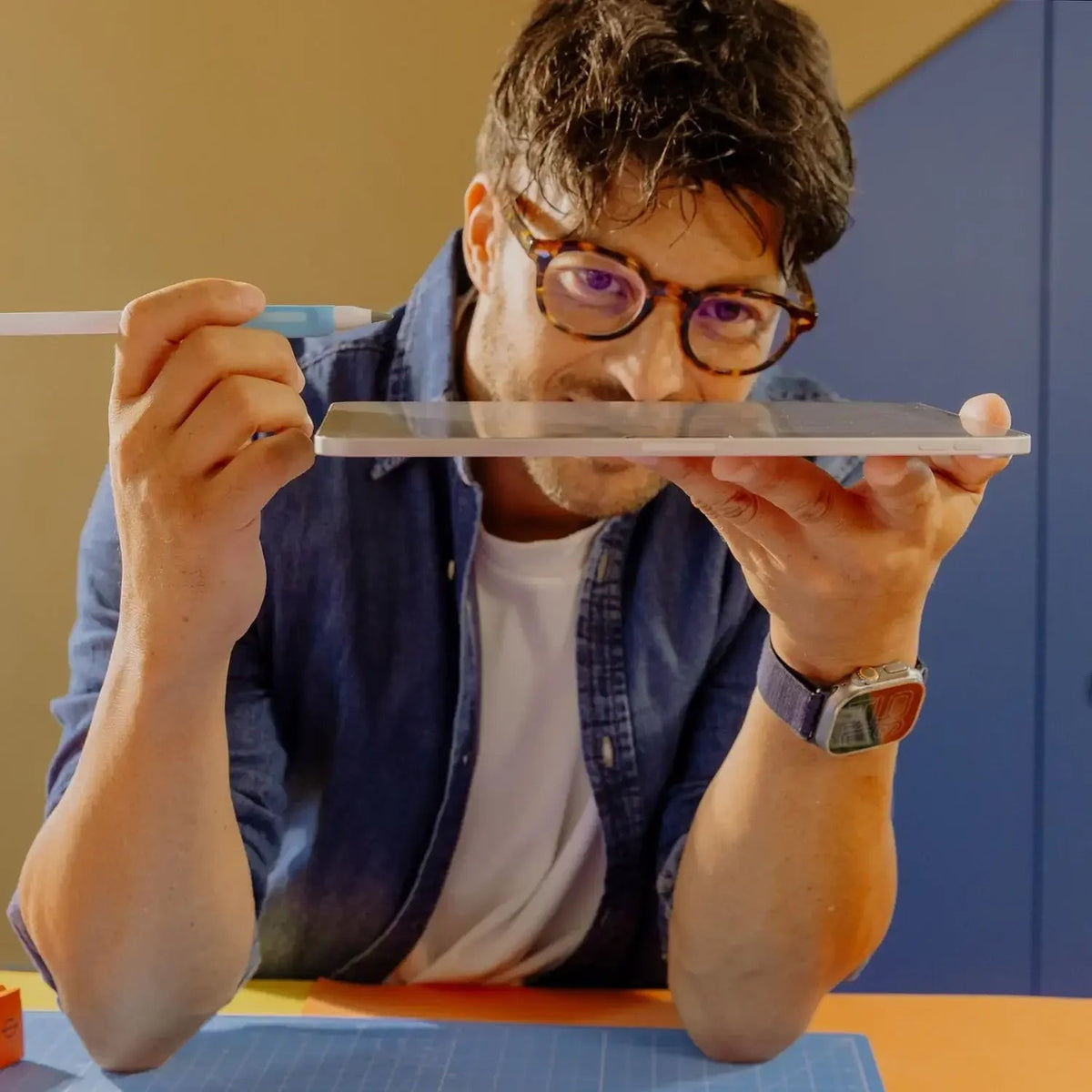 Mężczyzna z okularami trzyma tablet i długopis, idealny dla home office i efektywności pracy